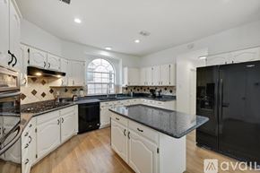 Plano house for rent - A kitchen with white cabinets and a black countertop.