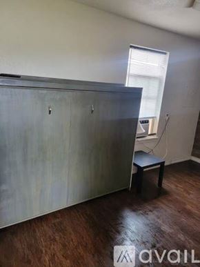 Aransas Pass apartment for rent - A room with a wooden floor and a grey wall with a cabinet and a small table.