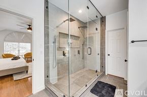Rowlett house for rent - A bathroom with a walk-in shower and a bedroom with a bed and a ceiling fan.