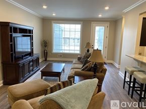 New Hartford townhouse for rent - A living room with a brown wooden entertainment center and a striped chair.