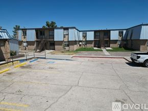 Fort Stockton apartment for rent - A parking lot in front of a building with a car parked on the right side.