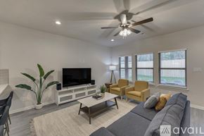 Dallas house for rent - A living room with a grey couch, a television, and a ceiling fan.