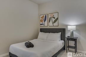 Dallas house for rent - A bedroom with a bed, a nightstand with a lamp, and two framed pictures on the wall.