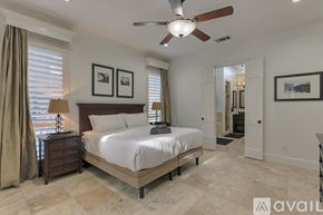 Mesquite house for rent - A bedroom with a large bed, a ceiling fan, and a dresser with a lamp on it.