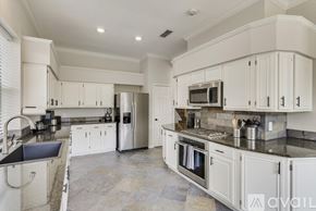 Grand Prairie house for rent - A kitchen with white cabinets and a black countertop.