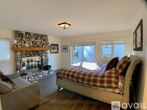 Ketchum house for rent - A bedroom with a stone fireplace and a bed with a plaid comforter.