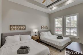 Rowlett house for rent - A bedroom with two beds, one with a grey blanket on it.