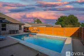 Rowlett house for rent - A pool surrounded by a concrete patio and a wooden fence.