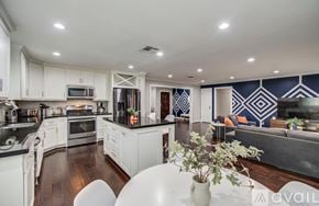 Houston house for rent - A bedroom with a large bed, a nightstand with a lamp, and a dresser with a mirror.