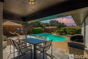 Dallas house for rent - A patio with a table and chairs overlooking a pool.