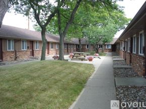 Toledo apartment for rent - A grassy area in front of a building with a tree and a bench.