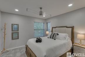 Rowlett house for rent - A bedroom with a large bed, a window with blinds, and a nightstand with a lamp.