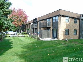 Maumee apartment for rent - A building with a balcony and a green lawn in front.