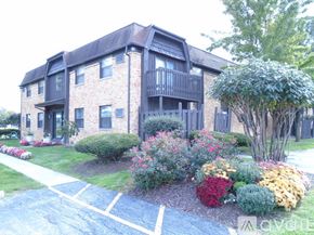 Maumee apartment for rent - A brick building with a balcony and a small garden in front.