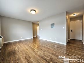 Chicago apartment for rent - A spacious room with wooden flooring and white walls.