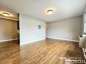 Chicago apartment for rent - A spacious room with wooden flooring and a sliding door.