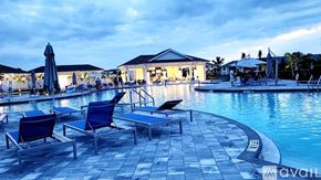 Punta Gorda condo for rent - A poolside area with lounge chairs and umbrellas is lit up at dusk.