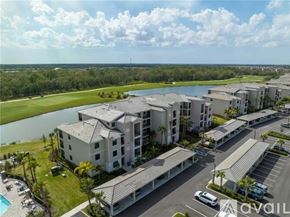 Bradenton condo for rent - A large building complex with a pool and a parking lot in front.