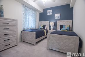 Bradenton condo for rent - Two twin beds in a bedroom with a dresser and a window with curtains.