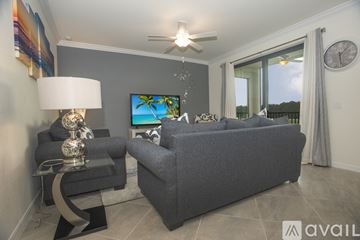 Bradenton condo for rent - A living room with a grey couch, a glass table with a lamp, and a painting on the wall.
