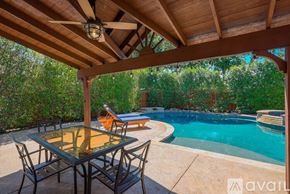 Rowlett house for rent - A table and chairs are set up on a patio with a pool in the background.