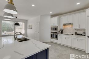Rowlett house for rent - A modern kitchen with white cabinets and a large island.