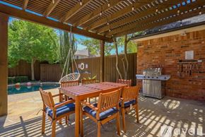 Plano house for rent - A wooden table and chairs are set up on a patio with a pool in the background.