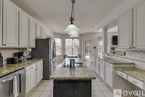 Plano house for rent - A kitchen with white cabinets and a granite countertop.