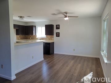 Pflugerville house for rent - A room with a ceiling fan and a kitchen area with a counter and cabinets.