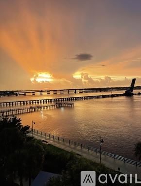 Bradenton condo for rent - A sunset view with a bridge and a plane in the sky.