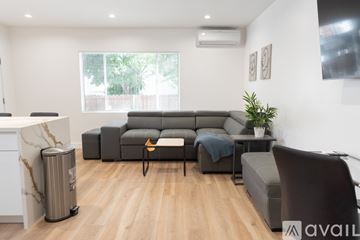 Los Angeles apartment for rent - A living room with a grey sofa, a black chair, and a small table with a plant on it.