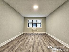 Chicago apartment for rent - A spacious room with a window and a wooden floor.
