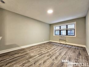 Chicago apartment for rent - A spacious room with wooden flooring and a white ceiling.