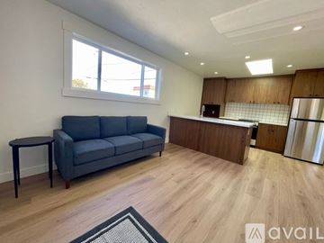 Eureka house for rent - A living room with a grey sofa and a kitchen area with a refrigerator in the background.
