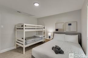 Garland house for rent - A bedroom with a white bed, two bunk beds, and a nightstand with a lamp.