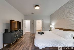 Haltom City house for rent - A bedroom with a large bed and a TV cabinet.