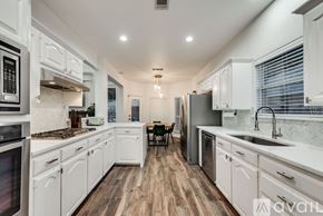 Haltom City house for rent - A kitchen with white cabinets and a wooden floor.