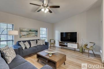 Dallas house for rent - A living room with a grey couch, a wooden coffee table, a television, and a painting on the wall.
