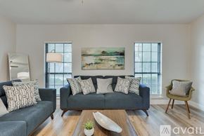 Dallas house for rent - A living room with a grey couch, a wooden coffee table, and a painting on the wall.