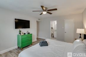 Dallas house for rent - A bedroom with a green dresser and a flat screen TV mounted on the wall.
