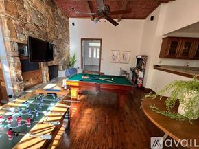 Dallas house for rent - A room with a pool table, a fireplace, and a television.