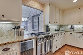 Dallas house for rent - A kitchen with white cabinets and a granite countertop.