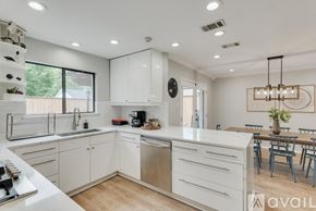 Plano house for rent - A modern kitchen with white cabinets and a wooden floor.