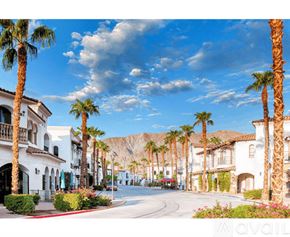 La Quinta condo for rent - A street lined with palm trees and white buildings.
