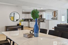 Plano house for rent - A modern kitchen with a dining table set with a blue vase and a plant.