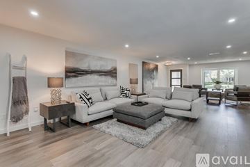 Dallas house for rent - A modern living room with a large painting on the wall and a variety of seating options.