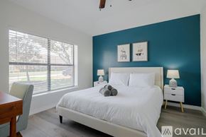 Richardson house for rent - A bedroom with a white bed and a wooden table.