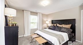Blacklick apartment for rent - A bedroom with a large bed and a nightstand with a lamp.