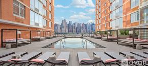 North Bergen condo for rent - A pool area with sun loungers and a view of a city skyline.