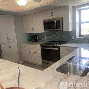 North Fort Myers condo for rent - A kitchen with white cabinets and a black stove top oven.